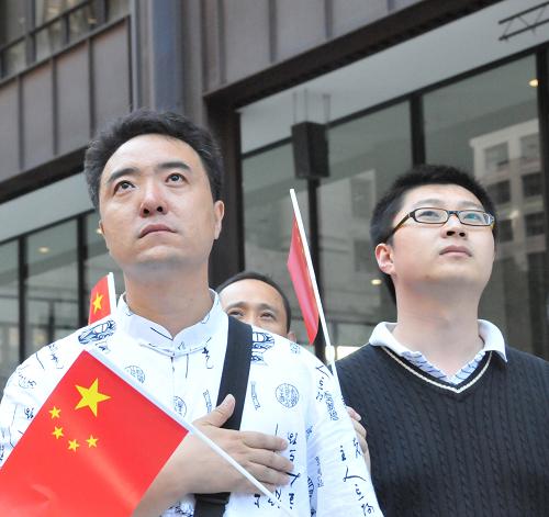 9月30日,在美國芝加哥市中心戴利廣場,一名中國留學(xué)生(左)手持國旗參加國慶升旗典禮。新華社發(fā)(蔣新彤?dāng)z)
