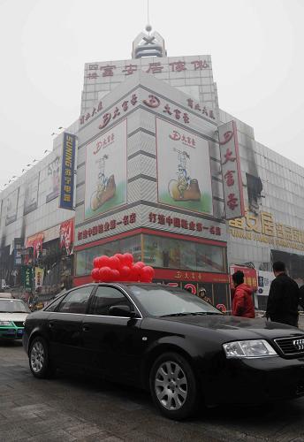 11月7日,一輛婚車從火災(zāi)后的吉林商業(yè)大廈前經(jīng)過。新華社記者褚曉亮攝