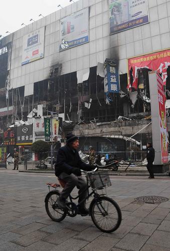 11月7日,一名行人騎著自行車從火災(zāi)后的吉林商業(yè)大廈前經(jīng)過。新華社記者褚曉亮攝