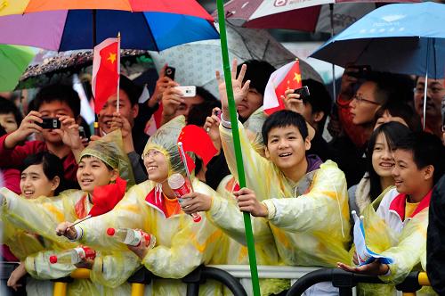 10月23日,當(dāng)?shù)貙W(xué)生冒雨為亞運(yùn)火炬?zhèn)鬟f加油助威。新華社記者梁旭攝