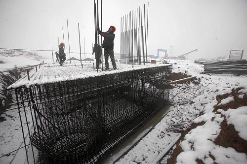 2月28日,工人冒雪在河南省洛陽市跨伊河大橋工地進行橋墩施工。