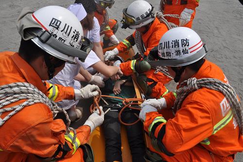 4月28日,消防人員對(duì)受傷人員進(jìn)行援救。4月28日,四川綿陽(yáng)舉行大型跨區(qū)域地震救援拉動(dòng)演習(xí)。演習(xí)內(nèi)容為當(dāng)日清晨7時(shí)許,四川綿陽(yáng)市119指揮中心多部接警電話(huà)接到“報(bào)警”稱(chēng),江油市清蓮鎮(zhèn)發(fā)生里氏7級(jí)地震,造成建筑倒塌,大量“人員”被埋壓,請(qǐng)求消防官兵快速增援。綿陽(yáng)消防官兵不到半個(gè)小時(shí)集結(jié)上百名消防官兵,通過(guò)車(chē)運(yùn)和徒步前進(jìn)到達(dá)演習(xí)現(xiàn)場(chǎng)。經(jīng)到達(dá)現(xiàn)場(chǎng)的消防官兵搜尋,發(fā)現(xiàn)五名群眾被埋壓,消防官兵立即對(duì)被困人員展開(kāi)營(yíng)救,橫向頂撐破拆救援、狹小空間救援、擔(dān)架一點(diǎn)吊救援、大繩斜下?lián)芫仍染仍椒?,不到兩個(gè)小時(shí),五名被埋壓的群眾被安全救出。在5·12地震三周年之際,本場(chǎng)演習(xí)再現(xiàn)了綿陽(yáng)消防官兵的救援能力。新華社發(fā)(王二來(lái) 攝)