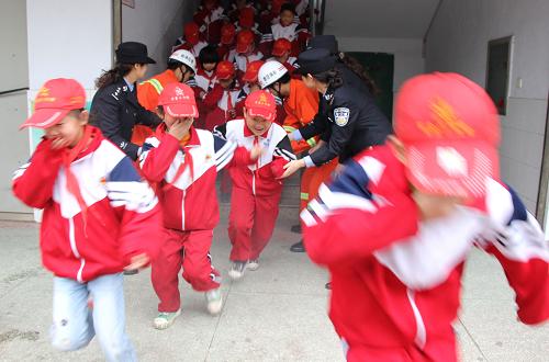 11月7日,在山東棗莊市紅旗小學(xué),學(xué)生在民警的幫助下進(jìn)行火場(chǎng)逃生演練。新華社 發(fā)