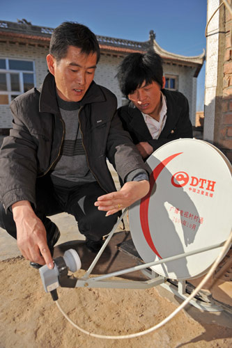 寧夏銀川市永寧縣文化旅游廣播電視局工作人員(左)向村民講解衛(wèi)星電視使用方法(2月22日攝)。新華社記者 王鵬 攝