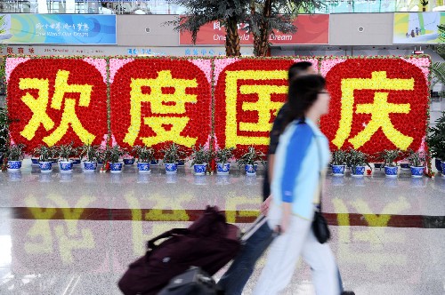 10月5日,兩名旅客從機(jī)場(chǎng)候機(jī)樓“歡度國(guó)慶”布景前經(jīng)過(guò)。“十一”黃金周進(jìn)入最后一天,青島流亭國(guó)際機(jī)場(chǎng)迎來(lái)返程客流高峰,計(jì)劃執(zhí)行航班258架次。 新華社記者 李紫恒 攝