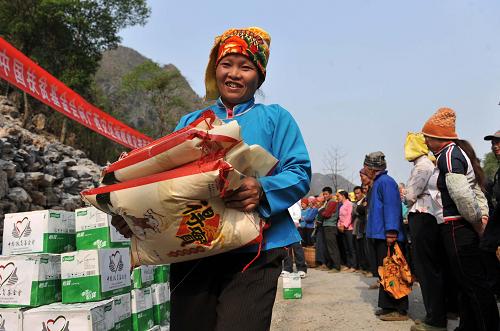 3月27日,在廣西百色市凌云縣泗城鎮(zhèn)后龍村,一名瑤族婦女在領(lǐng)取大米。新華社記者 周華 攝