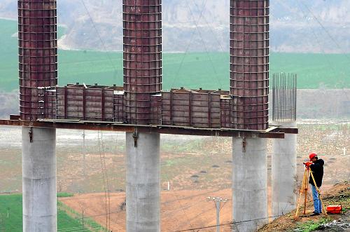 3月30日,在連霍高速公路改擴建工程洛陽境內(nèi)的一個工地上,一名技術(shù)人員在測量橋樁的方位。新華社記者王頌攝
