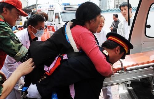 6月1日,列車員把玉樹地震傷員索南卓瑪(中)背上救護車。新華社記者 侯德強 攝
