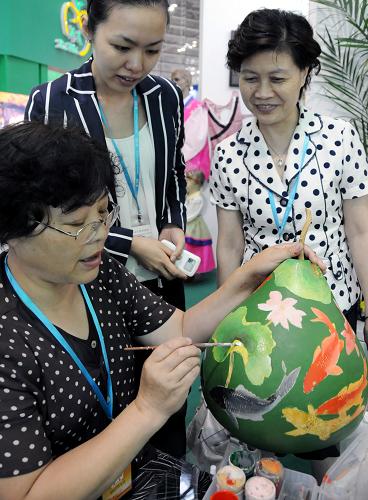 6月18日,吉林長春民間藝術(shù)家張鐵梅(左)現(xiàn)場創(chuàng)作葫蘆藝術(shù)畫。新華社記者 來建強(qiáng) 攝
