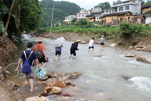 6月18日,在廣西金秀瑤族自治縣三江鄉(xiāng)合興村,人們在涉水過河。新華社發(fā)(鄔鵬攝)