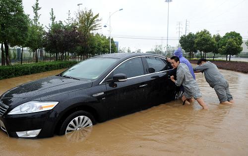 7月12日,在安徽省六安市,市民將在路面積水中熄火的汽車推出。 始于7月10日的連續(xù)降雨造成六安市部分城區(qū)不同程度積水,金寨、霍山等南部山區(qū)部分鄉(xiāng)鎮(zhèn)受災(zāi)。 新華社發(fā)(陳力 攝)