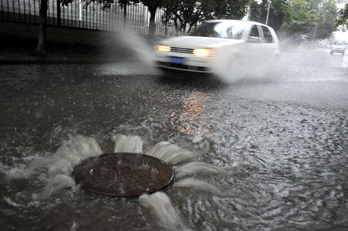 7月12日,在安徽省合肥市,一輛汽車在被大水淹沒(méi)的道路上涉水行進(jìn),水還不斷從窨井中涌上路面。新華社發(fā)(楊曉原 攝)