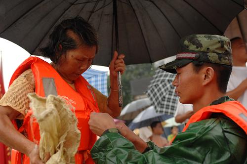 7月15日,在江西鄱陽縣,武警官兵在幫助災(zāi)民轉(zhuǎn)移到安全地帶。新華社記者周密攝