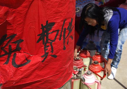 8月15日,甘肅岷縣居民張何慧琴在免費(fèi)供水點(diǎn)準(zhǔn)備熱水。新華社發(fā)(劉瀟 攝)