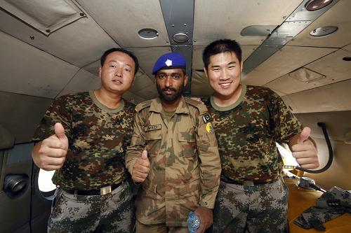 10月8日,在巴基斯坦海德拉巴洪水災區(qū),中國人民解放軍直升機救援隊隊員與巴軍投放員加瓦德合影留念。新華社記者李翔攝