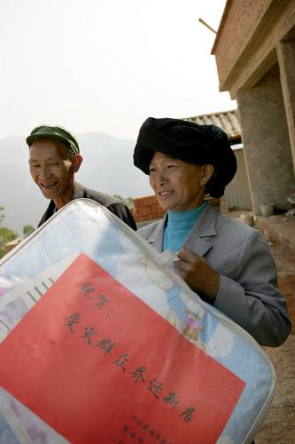 4月30日,西舍路鄉(xiāng)龍崗羊頭山安置點一戶遷入新居的受災群眾高興地拿到楚雄市政府送來的棉被。新華社發(fā)(施思思 攝)