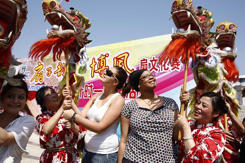 5月1日,一支老年舞蹈隊(duì)的隊(duì)員教幾名外國(guó)游客舞龍燈。新華社記者 裴鑫 攝