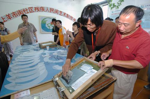 5月25日,中國書畫研究院會(huì)員、肢殘人士許峰(右二)指導(dǎo)肢殘人士吳永利(右一)學(xué)習(xí)扇面絲網(wǎng)印刷技術(shù)。當(dāng)日,杭州首家社區(qū)殘疾人民間藝術(shù)制作中心在上城區(qū)紫陽街道上羊市街社區(qū)成立。這家制作中心是社區(qū)為殘疾下崗工人搭建的創(chuàng)業(yè)平臺(tái),首批12名殘疾下崗工人在這里接受培訓(xùn)后將從事扇藝、折紙、航模等工藝品的加工制作。新華社發(fā)(施健學(xué) 攝)