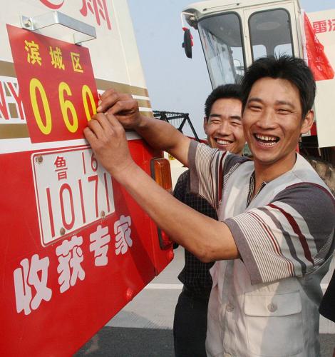 5月26日,跨區(qū)作業(yè)農(nóng)機(jī)手唐兵田(右)給自己的小麥聯(lián)合收割機(jī)貼上標(biāo)簽。新華社發(fā)(李榮新 攝)