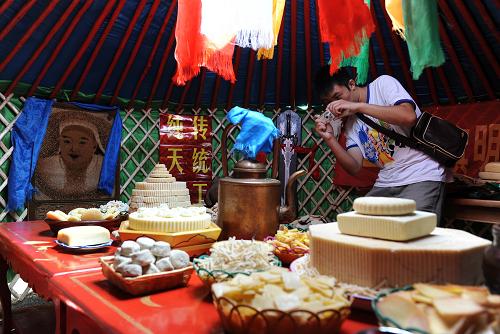 7月31日,一名旅游者在內(nèi)蒙古正鑲白旗察哈爾旅游文化周開幕式上欣賞造型各異的蒙古族傳統(tǒng)奶食。 新華社記者 張領(lǐng) 攝