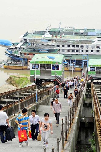 8月4日,在三峽壩區(qū)太平溪港區(qū)客運(yùn)碼頭,來自重慶方向的乘客走下輪船后,將改乘汽車到宜昌后再坐船下行。受長江上游持續(xù)暴雨天氣影響,三峽入庫流量猛增。8月4日14時(shí),入庫流量達(dá)每秒45000立方米。三峽船閘于8月3日起停止通航,今年夏季以來首次啟動(dòng)翻壩運(yùn)輸。目前沒有發(fā)生旅客和貨車滯留現(xiàn)象。 新華社發(fā)(黃翔 攝)
