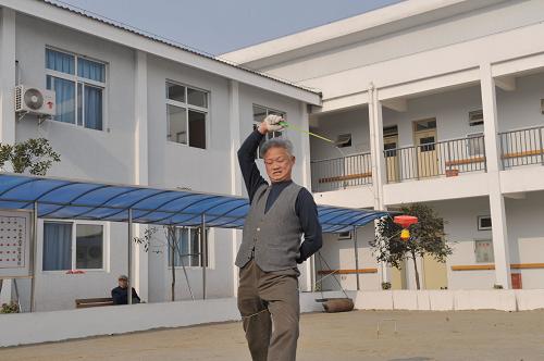 1月27日,一名老人在救助中心院里抖空竹。新華社記者 魯鵬 攝