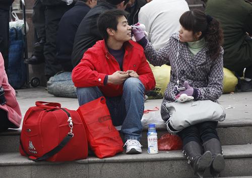 1月30日,將返鄉(xiāng)過年的河南商丘人袁冠軍(左)在候車時與女友一起分享音樂。新華社記者 裴鑫 攝