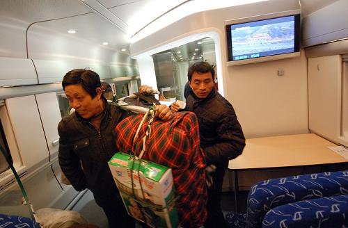 2月2日,在從杭州始發(fā)至南昌的動車組D297次列車上,來自江西省南昌縣武陽鎮(zhèn)的農(nóng)民工李水全挑著行李走進車廂。新華社發(fā)(黃宗治 攝)