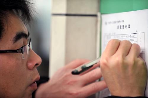 2月24日,一位求職者在廣州市人力資源市場中心市場外填寫求職登記表。新華社記者 陳曄華 攝