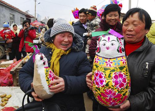 3月17日,兩位農(nóng)婦在山東濱州市惠民縣皂戶李鄉(xiāng)火把李村的“泥娃娃廟會”上選購泥娃娃。新華社發(fā)(董乃德 攝)