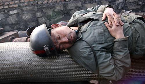 救援人員葉西海,56歲(4月1日攝)。因十分疲憊,他躺在礦井出口處睡著了。他3月28日下午到達王家?guī)X礦參加救援工作,每天工作十幾個小時。 新華社記者 高學余 攝
