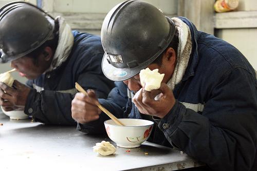 4月1日, 這兩位救援人員正在吃晚飯,他們早上6點下井直至下午5點才上來。我問其中一位師傅的名字,他的眼里立即充滿了淚花,并用手中饅頭擋住臉。我實在不忍心再按下快門,便走到他身后,用手輕輕地拍拍他的后背,表示歉意。 新華社記者 高學余 攝
