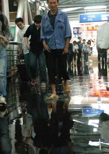 6月1日,在北京西客站過街天橋上,人們趟過積水橋面。當(dāng)晚,北京降下雷陣雨,沒有排水設(shè)施的西客站北廣場前過街天橋積水嚴(yán)重,致使來往旅客通行不便。新華社記者 葉平凡 攝