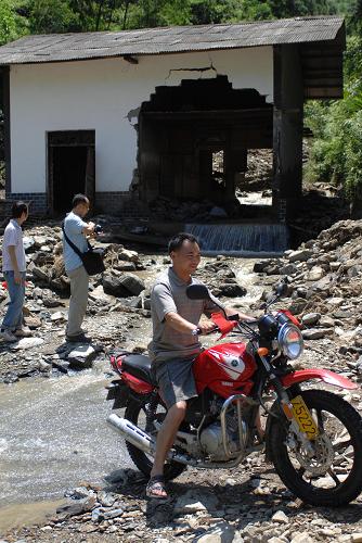 7月20日,陜西省嵐皋縣四季鄉(xiāng)的一段公路處,山水經(jīng)過路邊房屋流到路面上。新華社記者 丁海濤 攝