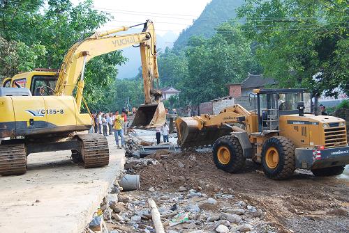 7月27日,大型機(jī)械在橋耳溝村一組搶修被沙石填埋的道路。新華社記者 陳昌奇 攝