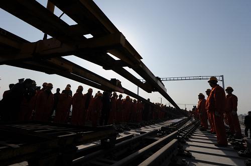 11月29日,承擔(dān)石武鐵路客運專線的中國中鐵第四工程局建設(shè)者開始鋪軌作業(yè)。當(dāng)日,國家鐵路重點建設(shè)工程石(家莊)武(漢)鐵路客運專線在河南省許昌段開始鋪軌。石武鐵路客運專線全長840公里,設(shè)計時速350公里,輸送能力為單向8000萬人/年,是北京至武漢、廣州到香港鐵路客運專線的重要組成部分,也是我國縱貫?zāi)媳本€路里程最長、輻射范圍最廣的快速客運通道。石武鐵路客專線鋪軌工程將于2011年底完成。新華社記者 王雷 攝