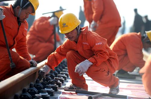 11月29日,承擔(dān)石武鐵路客運專線的中國中鐵第四工程局建設(shè)者為第一根鐵軌擰上螺絲釘。新華社記者 王雷 攝
