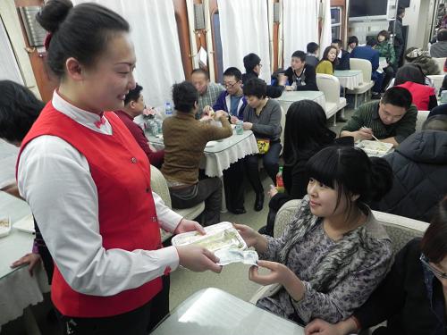1月27日,K7909次列車餐車服務(wù)人員為一位旅客送來便宜可口的學(xué)生餐。新華社記者 鄒儉樸 攝