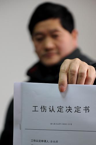 1月13日,湖北省宣恩縣人力資源和社會(huì)保障局的一名工作人員展示工傷認(rèn)定決定書(shū)。新華社發(fā)(宋文 攝)