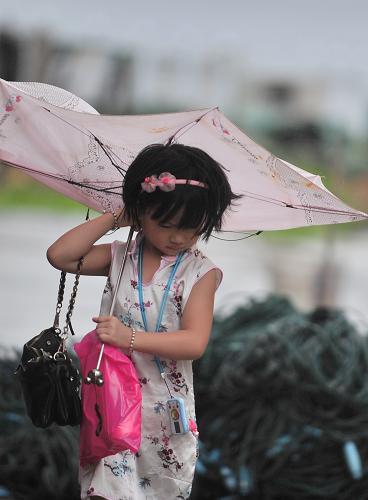 這是在臺(tái)風(fēng)“蘇拉”登陸點(diǎn)秦嶼鎮(zhèn),一名出行的小女孩撐著被風(fēng)打壞的雨傘(8月3日攝)。新華社記者 魏培全 攝