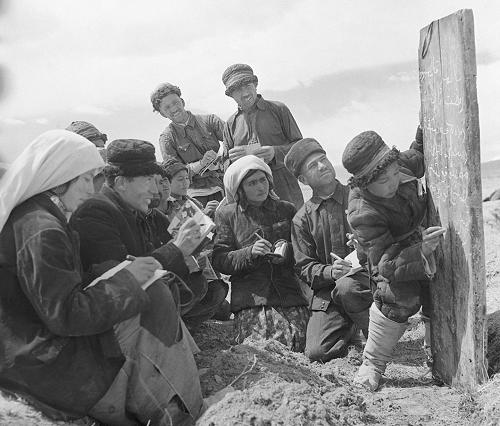 圖為1960年,新疆塔什庫爾干塔吉克族自治縣慕士塔格人民公社二大隊(duì)的社員在小學(xué)生的幫助下在田間學(xué)習(xí)文化。 新華社記者武純展攝(資料照片)