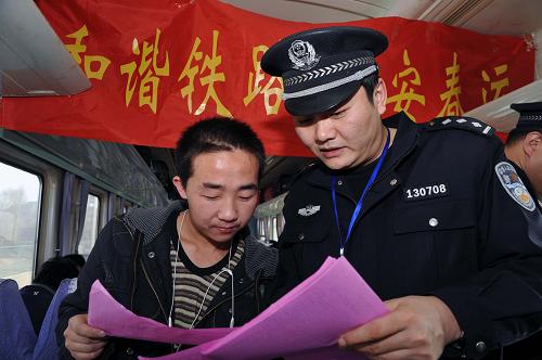 烏魯木齊鐵路公安處乘警支隊北京隊乘警李裕鋼(右)在給旅客講解宣傳單(2月2日攝)。新華社記者 趙戈 攝