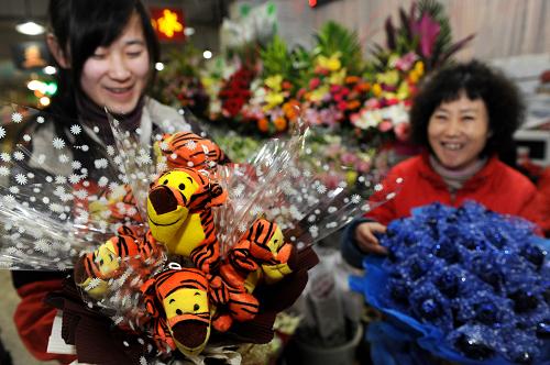 2月10日,青島南山花卉市場(chǎng)一位花店員工(左)在為情人節(jié)準(zhǔn)備卡通虎裝飾花束?;⒛暾鲁跻磺》晡鞣降那槿斯?jié),兩節(jié)碰頭為青島花卉市場(chǎng)帶來(lái)雙重商機(jī)。在青島的各花市,買(mǎi)花的人絡(luò)繹不絕,商家都提前預(yù)訂、采購(gòu)好了足夠數(shù)量的節(jié)慶年銷(xiāo)花和情人節(jié)必不可少的玫瑰,滿(mǎn)足“雙節(jié)”市場(chǎng)的需求。新華社記者 李紫恒 攝