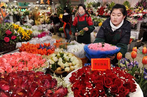 2月10日,青島南山花卉市場(chǎng)一位花店員工(右)在擺放鮮花。新華社記者 李紫恒 攝