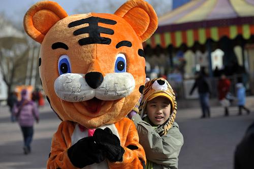 2月14日,在北京地壇春節(jié)廟會(huì)上,一名小朋友頭戴“虎帽”和卡通老虎合影。近日,北京各大廟會(huì)紛紛“開鑼”,不少游客和商販利用造型夸張、可愛的飾品裝扮自己,為喜慶、熱鬧的廟會(huì)更增添了時(shí)尚氣息。 新華社發(fā)(金碩 攝)