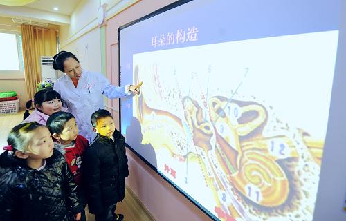 3月2日,來(lái)自湖南省兒童醫(yī)院聽(tīng)力中心的專(zhuān)家在給長(zhǎng)沙潤(rùn)澤府幼兒園的孩子講解耳朵的構(gòu)造。新華社記者 龍弘濤 攝