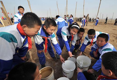 3月18日,銀川市興慶區(qū)司家橋小學(xué)的學(xué)生們?nèi)∷疁?zhǔn)備澆樹苗。新華社記者 劉泉龍 攝