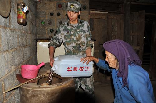 3月30日,在廣西靖西縣新甲鄉(xiāng)仁龍村,一名邊防戰(zhàn)士將飲用水送到87歲高齡的羅阿婆老人家里。 持續(xù)加劇的旱情在牽動著廣西駐軍官兵的心,連日來,廣西靖西邊防駐軍某部組織多個送水抗旱小分隊,將群眾急需的清潔飲用水送至旱區(qū),以解群眾燃眉之急。新華社發(fā)(趙京武 攝)