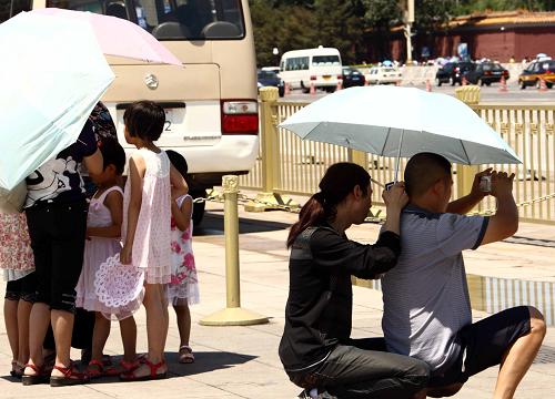 7月5日,天安門廣場(chǎng)的游人撐起遮陽(yáng)傘游覽、拍照。 新華社記者 高學(xué)余 攝