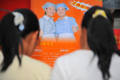 7月18日,兩位年輕女孩正在查看家政公司的招聘信息。新華社記者 劉續(xù) 攝